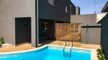 Un bâtiment moderne doté d’une piscine, d’un patio couvert et d’une clôture en bambou.