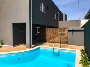 A modern building with a swimming pool, a covered patio, and a bamboo fence. - Vila Hotel By VimaHotels (Guimarães)