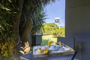 A breakfast tray on a table with croissants, a cup, a glass of orange juice, and a bowl of fruit, with a sign for 'VIA Hotel' in the background. - Vila Hotel By VimaHotels (Guimarães)