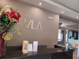 Un mostrador de recepción con un letrero que dice "VLA HOTEL" y un gran arreglo floral.