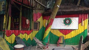 Un espacio al aire libre colorido con sillas y un tambor, rodeado por un muro vibrante con un diseño circular.