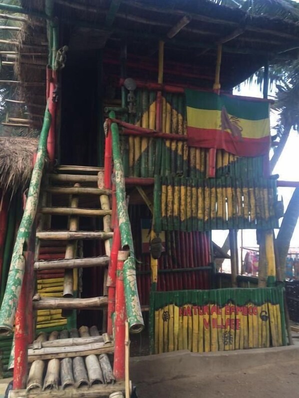 A bamboo structure with a ladder leading to a door, decorated with colorful fabric.