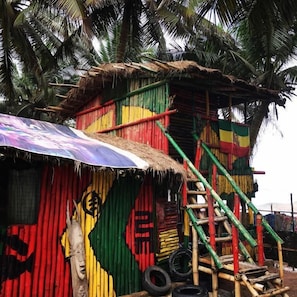 A colorful structure with a thatched roof, a staircase, and a large umbrella.