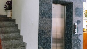 A modern elevator with a granite wall, a staircase, and a potted plant. - Golden Hotel Vung Tau (Ho Chi Minh City)
