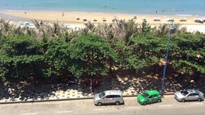 A beach with a row of parked cars and umbrellas along the shore. - Golden Hotel Vung Tau (Ho Chi Minh City)