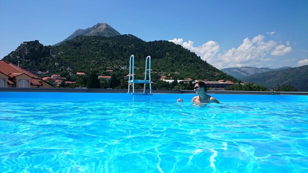 Ein Swimmingpool mit klarem, blauem Wasser, einer Leiter und einer Bergkulisse.