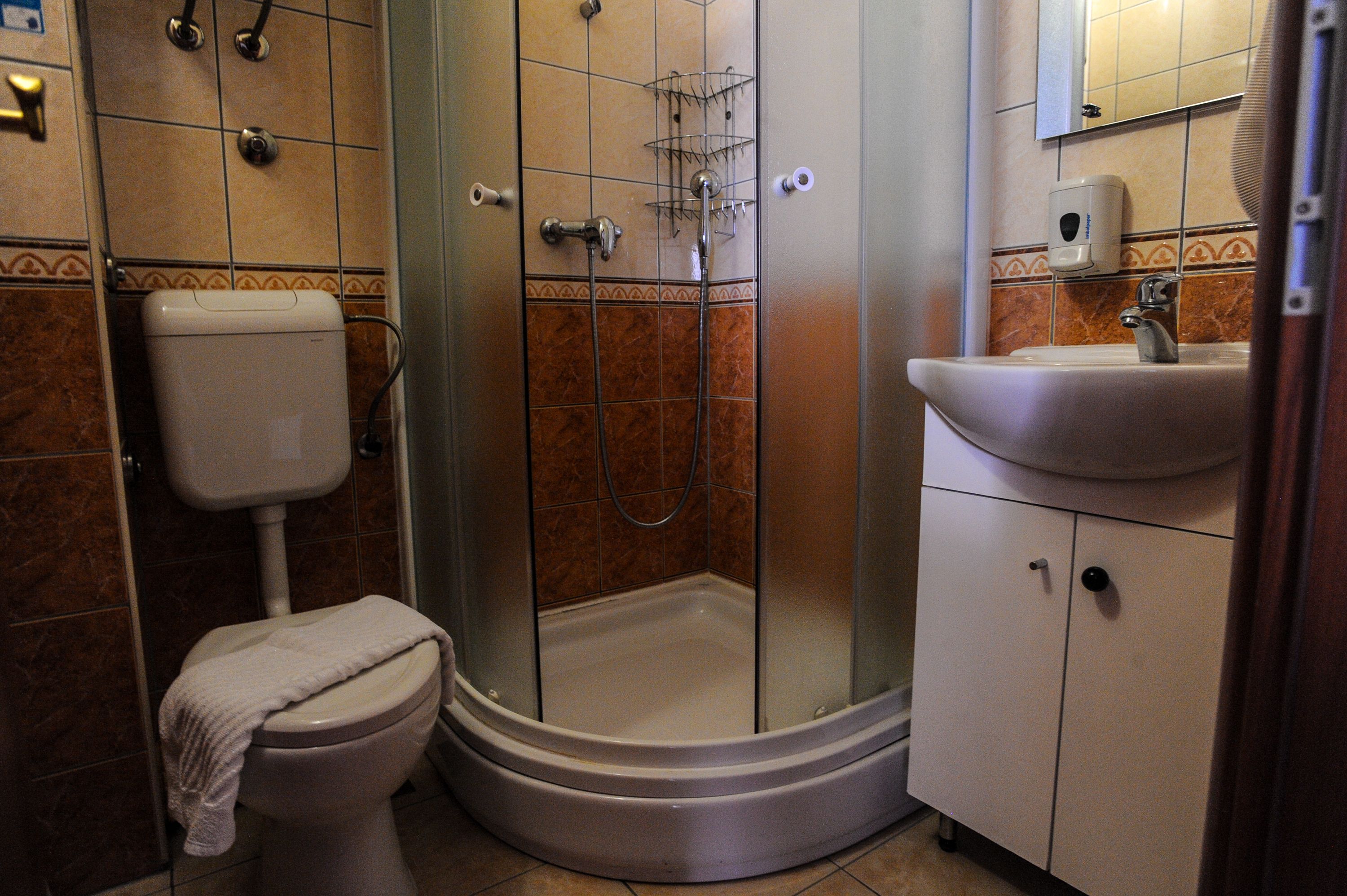 Une salle de bain comprenant des toilettes, une douche avec une porte en verre et un lavabo avec un distributeur de savon.