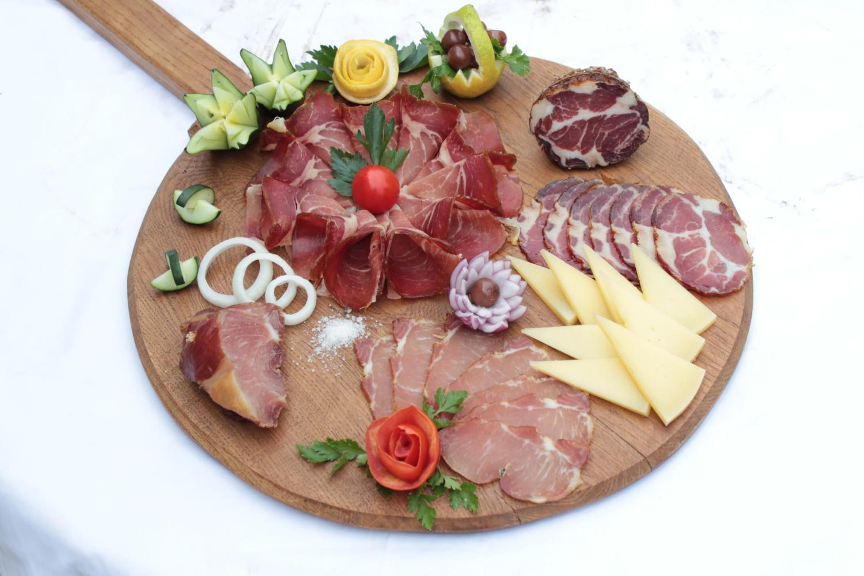 A charcuterie board with various meats, cheeses, and garnishes.