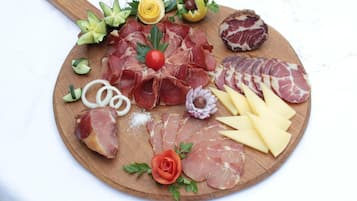 A charcuterie board with various meats, cheeses, and garnishes.