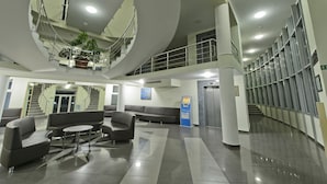 Un hall d’entrée spacieux avec un espace salon central, un escalier et une grande plante.