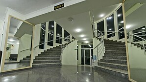 Un hall d'hôtel avec un escalier, une enseigne de bar et un distributeur d'eau.