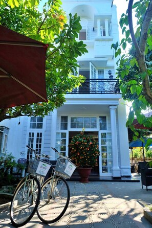 A white building with a balcony and a large flower display at the entrance. - Cochi Villa Hoi An (Da Nang)
