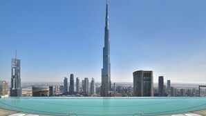 A high-rise building with a pool in the foreground and a cityscape in the background.
