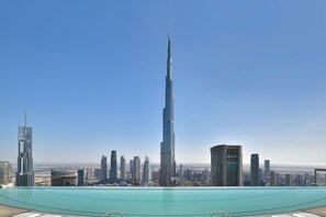A high-rise building with a pool in the foreground and a cityscape in the background.