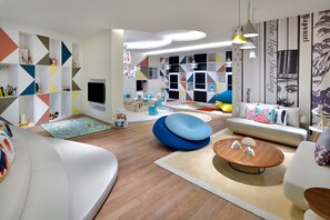 A modern living room with a white sofa, a wooden coffee table, and colorful geometric wall decorations.
