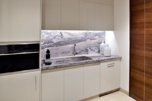 A modern kitchen with a marble backsplash, stainless steel appliances, and a wooden cabinet door.