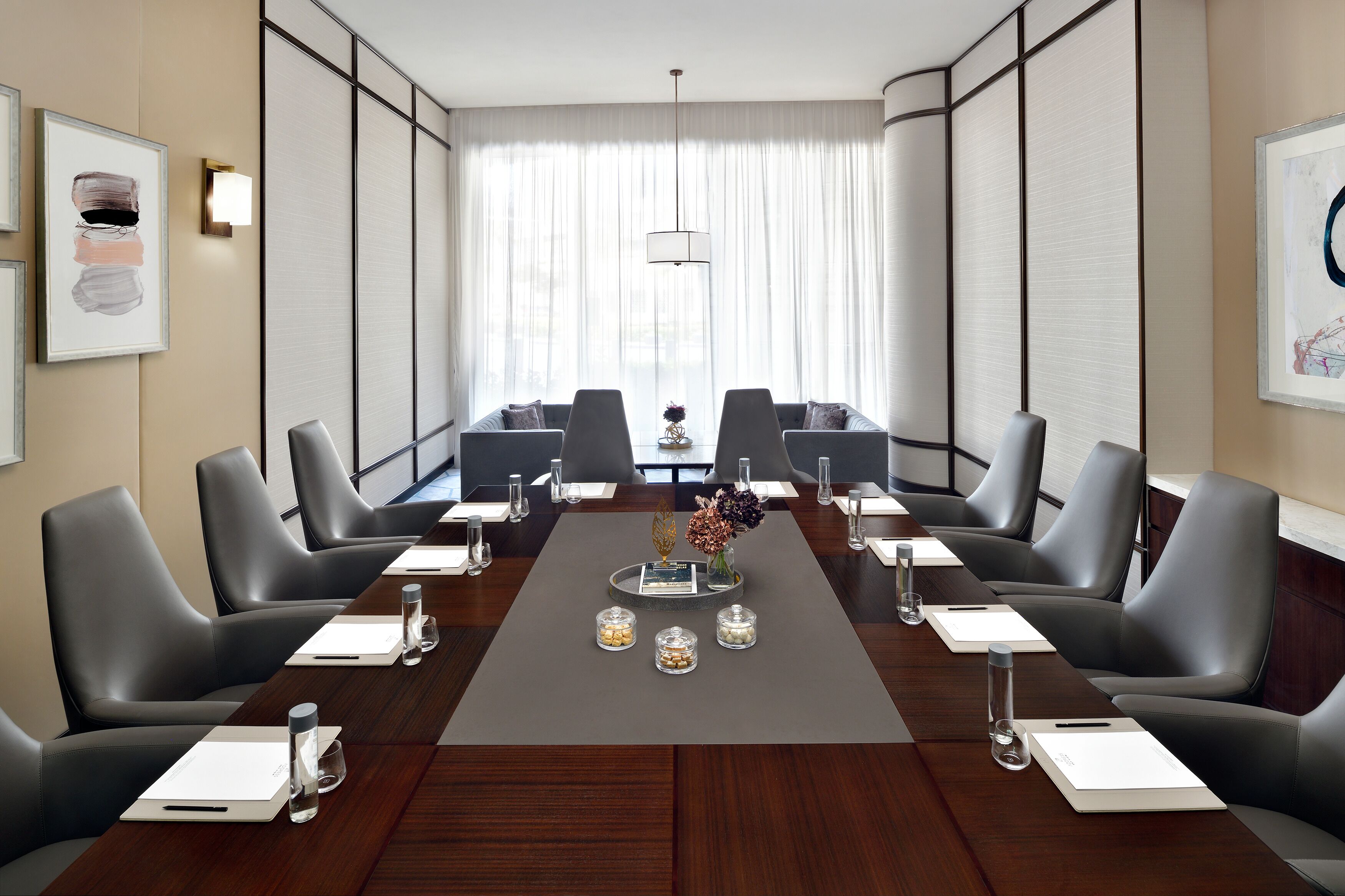 Een congreszaal met een lange tafel, meerdere stoelen en een decoratief middelpunt.