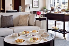 A well-appointed living room with a sofa, coffee table, and a tray of assorted pastries and sandwiches.