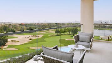 Un balcone con mobili in vimini, vista su un campo da golf e sullo skyline della città sullo sfondo.