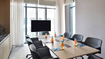 A conference room with a long table, black chairs, and a flat-screen TV.