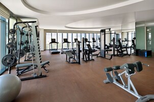 A spacious gym with various exercise equipment, large windows, and a modern design.