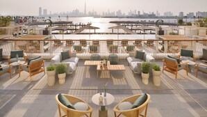 A rooftop terrace with outdoor seating, potted plants, and a view of the city skyline. - Vida Creek Harbour (Dubai)