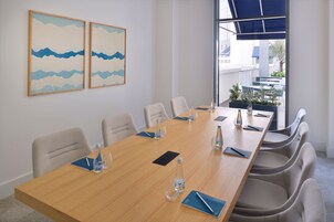 A conference room with a long table, chairs, water bottles, and a view of the outside.