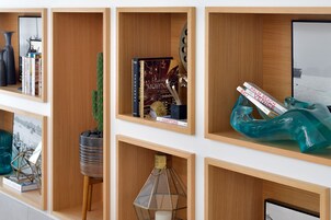 Una pared con varias estanterías de madera que exhiben libros, un cactus y objetos decorativos.