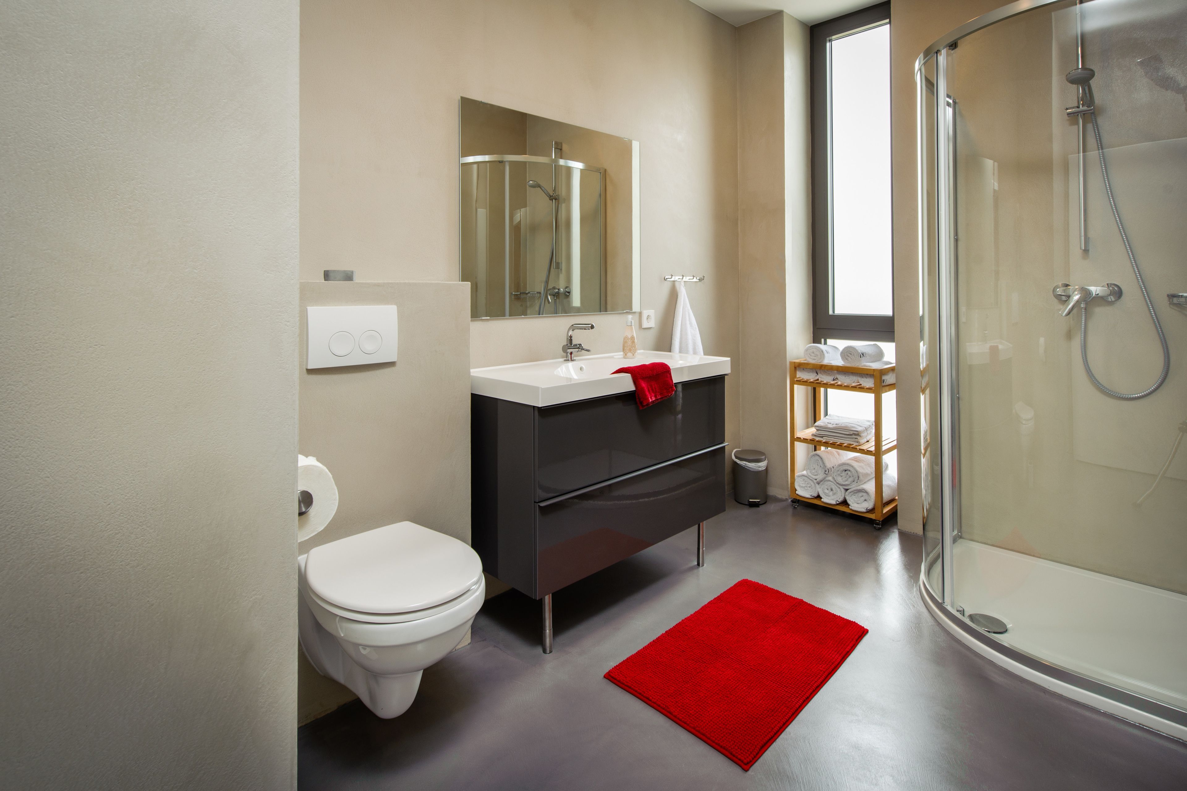 A modern bathroom with a toilet, sink, mirror, and shower.