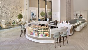 Eine moderne Hotelhalle mit Bar im Zentrum, Sitzgelegenheiten und einer Wanddekoration.