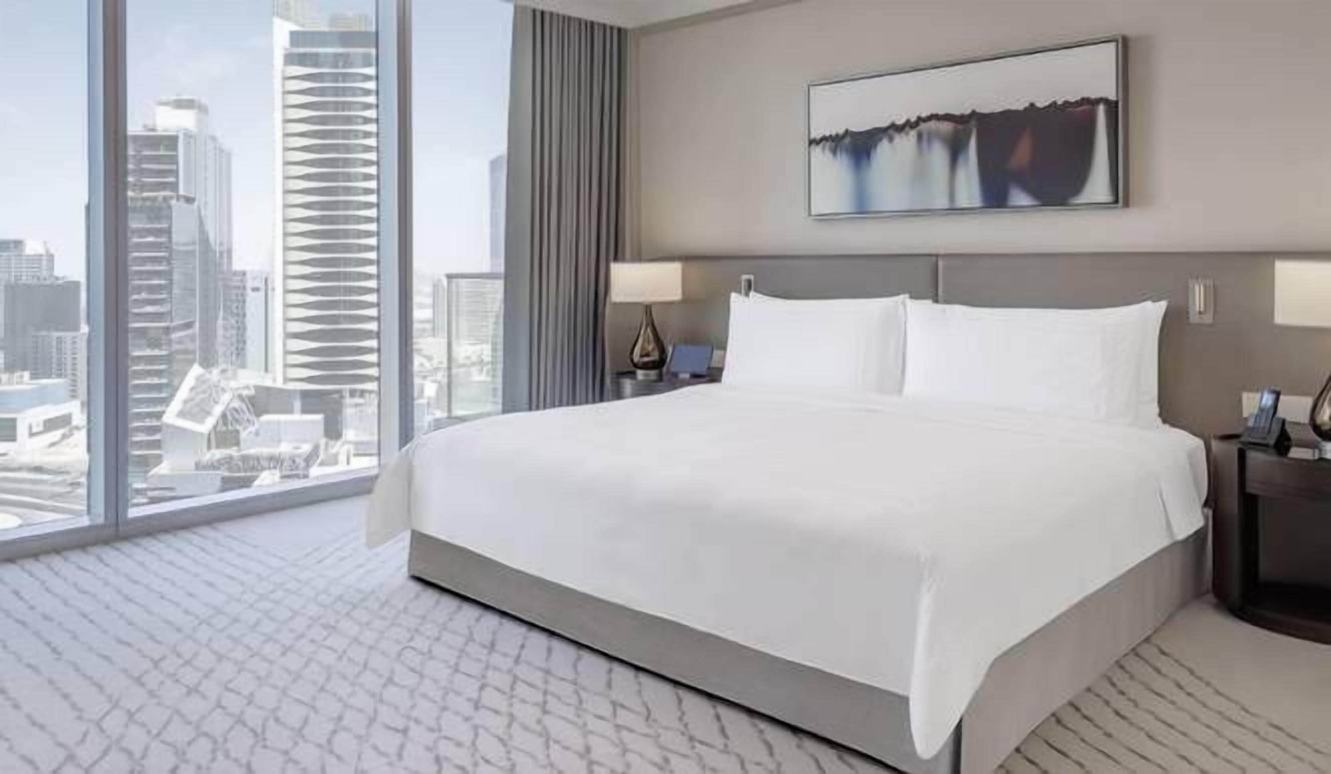 A hotel room with a large bed, a city view, and a modern design.