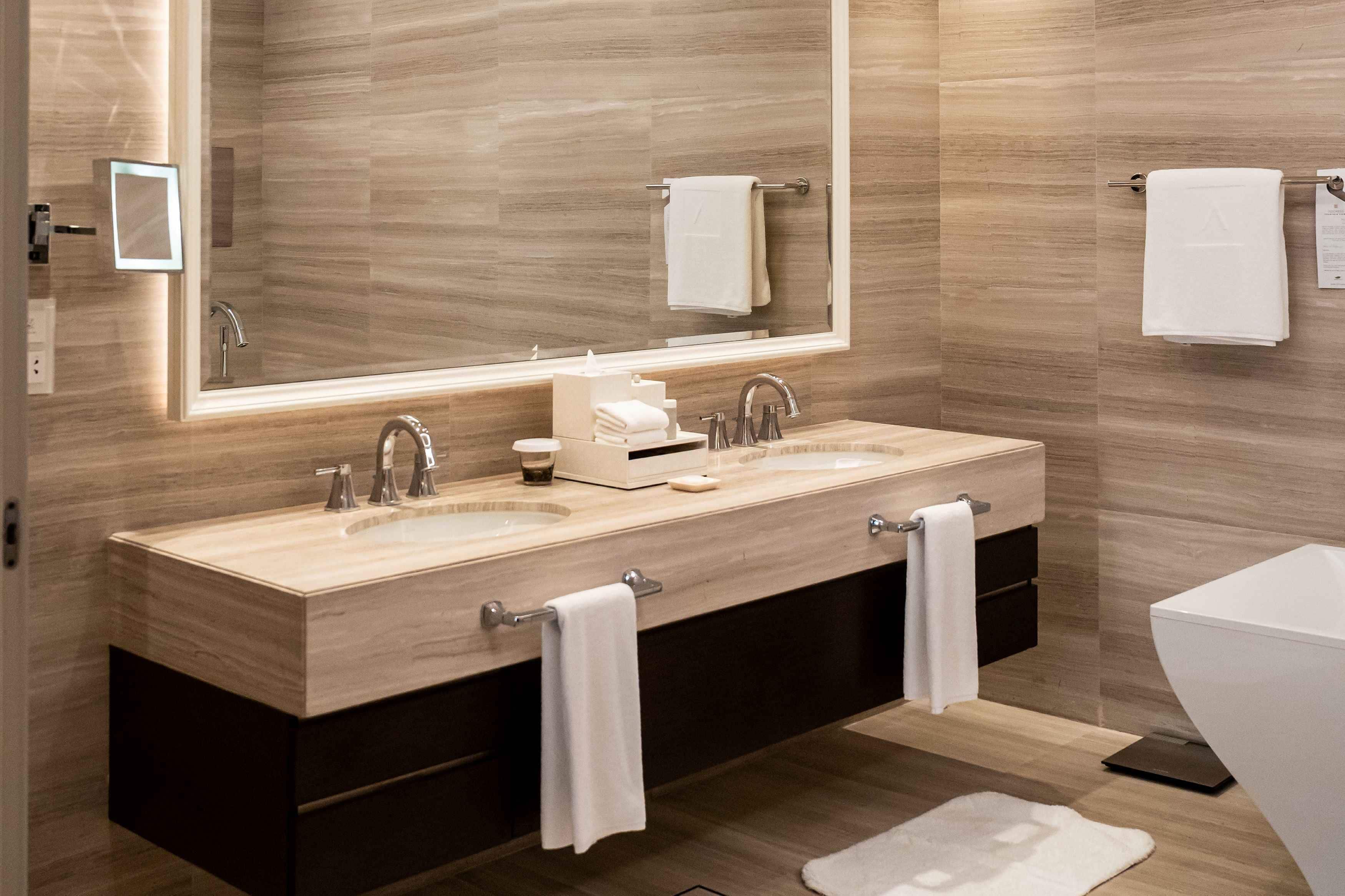A modern bathroom with two sinks, a large mirror, and a toilet.
