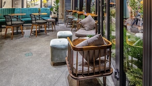 A modern interior with a brick wall, wooden ceiling, and hanging lamps. There are seating areas with tables and chairs. - Seahorse Han Market Da Nang Hostel by Haviland (Da Nang)