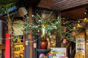 A storefront with a brick wall, a large potted plant, and various items on display including a sign with Japanese characters. - Seahorse Han Market Da Nang Hostel by Haviland (Da Nang)