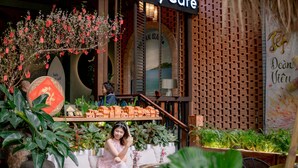 A cozy outdoor seating area with a brick wall, potted plants, and a small model village display. - Seahorse Han Market Da Nang Hostel by Haviland (Da Nang)