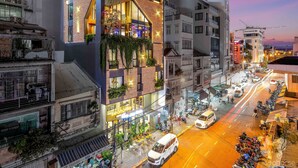 A hostel with a modern design, featuring a prominent neon sign, multiple balconies, and a vibrant urban street scene in the background. - Seahorse Han Market Da Nang Hostel by Haviland (Da Nang)