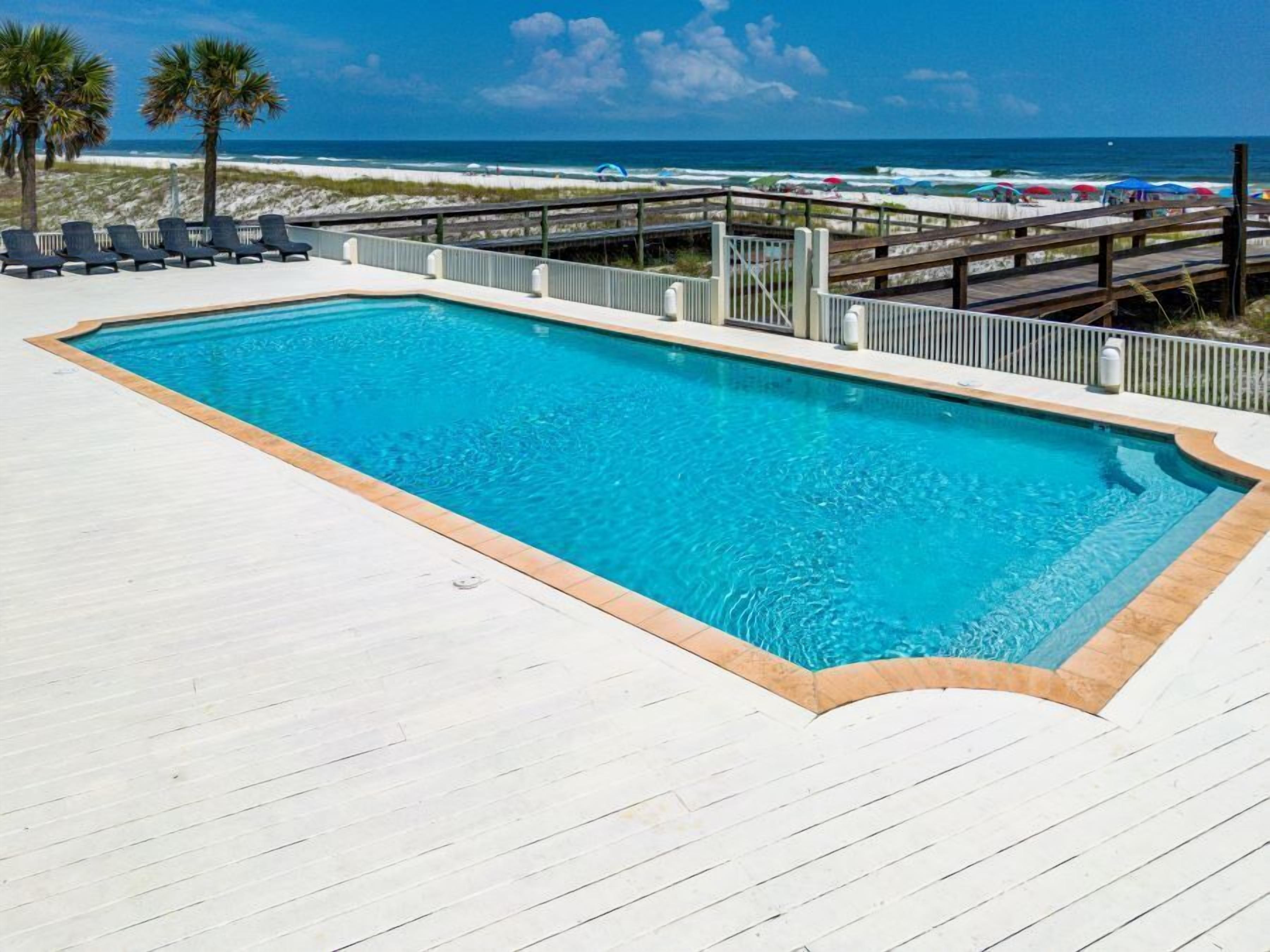 Una piscina rectangular con plataforma y baranda de madera.