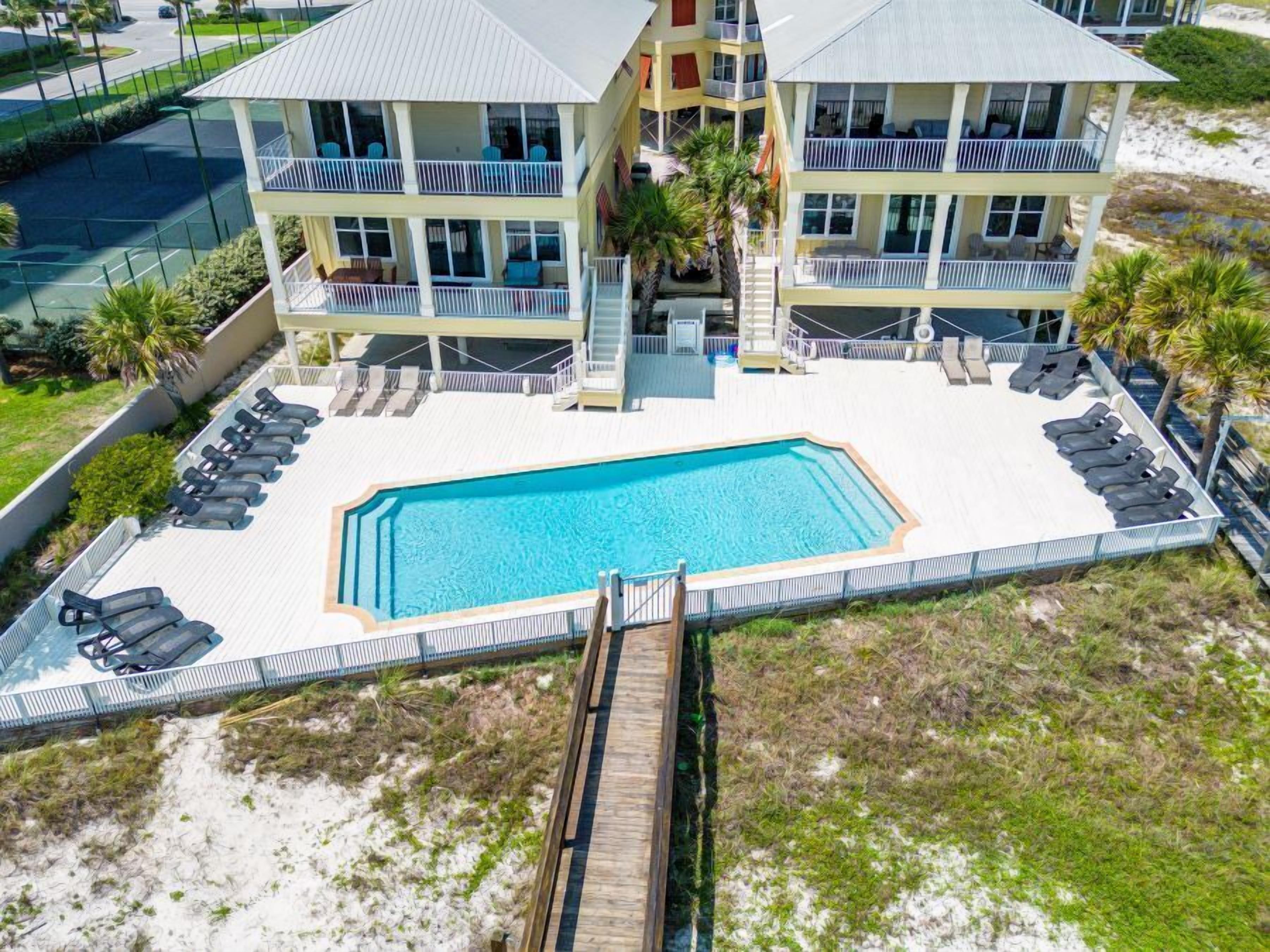 A two-story building with a pool and lounge chairs.