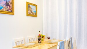 Une table à manger avec des chaises, une bouteille de vin et un saladier de fruits.
