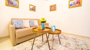 Un salon avec un canapé beige, des coussins à motifs, un vase rempli de fleurs jaunes et deux petites tables en bois.