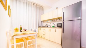 Une cuisine compacte comprenant une table à manger, des chaises, un réfrigérateur, un four à micro-ondes et des placards.