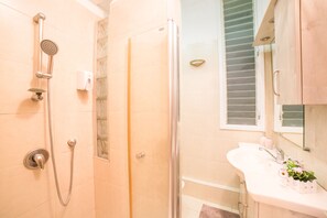 A bathroom with a shower, a sink, and a mirror.