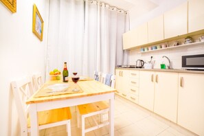 A kitchen with a wooden table, chairs, a microwave, and a sink.