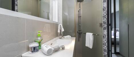 A modern bathroom with a glass-enclosed shower, a white sink, and a mirror.