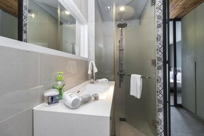A modern bathroom with a glass-enclosed shower, a white sink, and a mirror.