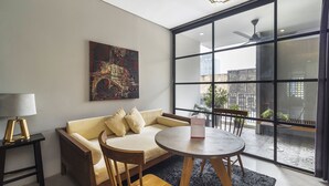 Una sala moderna con sofá, sillas, una mesa y un amplio ventanal con vista a la ciudad.