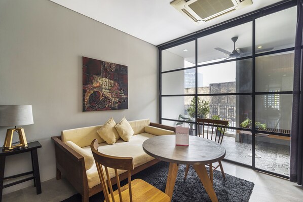 A modern living room with a sofa, chairs, a table, and a large window with a city view.