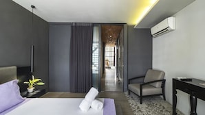 Una habitación de hotel moderna con una cama, una silla, un escritorio y un equipo de aire acondicionado.