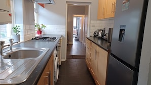 A modern kitchen with stainless steel appliances, wooden cabinets, and a central island. - Huku Kwetu - Ferndale House (Luton)