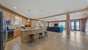 Una cocina amplia con armarios de madera, una isla central con taburetes y una isla grande con encimera azul.